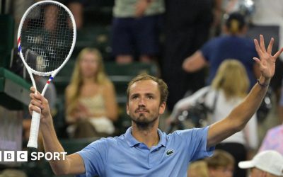 Daniil Medvedev holds up a tennis racquet